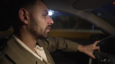 Gece araba kullanan bir adamın profili. Orta Doğulu bir erkek direksiyonlu araba kullanıyor. Aracın içi