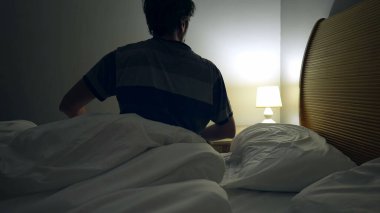 Adam yatağın başucundaki lambayı açıp yataktan kalkıyor. Gündoğumuna sabah erkenden başlayan kişi...