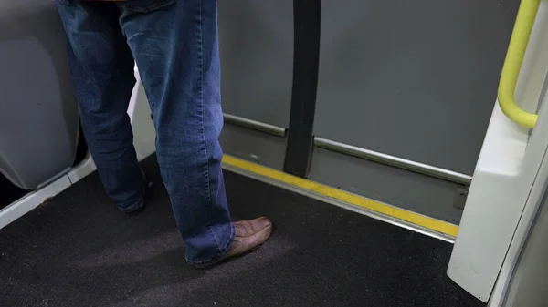 Person legs waiting by subway door in underground transportation. Passenger standing in standby inside train