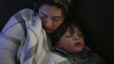 Mother and child asleep together on couch. Lifestyle family moment of parent and 3 year old small boy napping on sofa