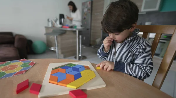 Creative child playing with puzzle blocks at home. One small 3 year old boy learning to play by himself at home apartment interior
