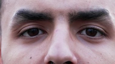 Dışarıdaki kameraya bakan bir Arap 'ın dramatik yakın çekimi. Makro, 20 'li yaşlarda ciddi bir Ortadoğu erkeği.
