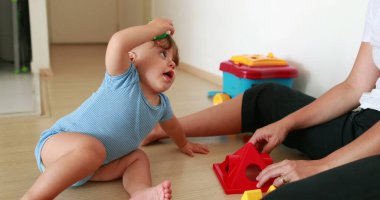 Cute baby playing indoors with toys. Mother and one year old infant relationship