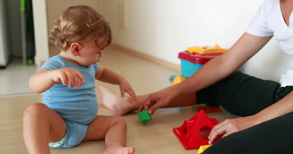 Cute baby playing indoors with toys. Mother and one year old infant relationship