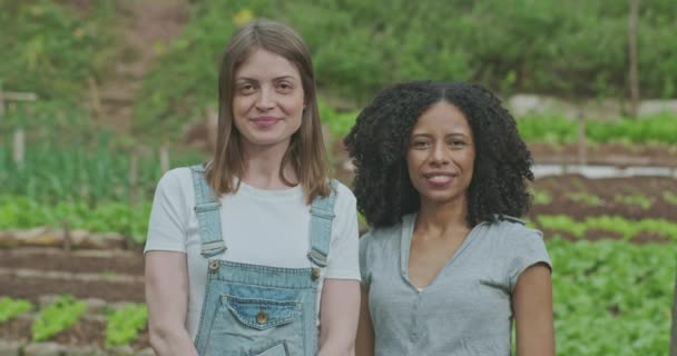 Zwei Junge Frauen Stehen Einem Üppigen Gemeinschaftsbauernhof Und Blicken Direkt — Stockvideo