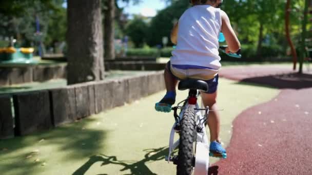 在阳光明媚的日子 孩子们在公园外面骑自行车的背面 积极参加户外运动的小男孩骑自行车 — 图库视频影像