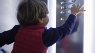 Asansördeki çocuk bisiklet tuşuna basıyor. Hafta sonu aktiviteleri sırasında eve gelen küçük bir çocuğun ev hayatı. Çocuk Yukarı Çıkıyor