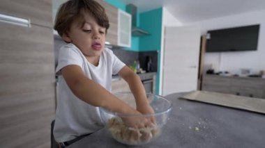 Çocuk mutfak masasında malzemeleri elle karıştırmayı öğreniyor. Küçük çocuk yemek hazırlıyor.