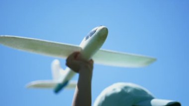 Çocuk parkın dışına oyuncak fırlatan bir planör tutuyor. Çocuk eli köpük uçak tutuyor. Uçan konsept