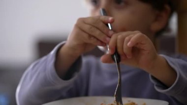 Çocuk ellerini kapayın, tabakta spagetti bükün. Küçük bir çocuk makarna yiyor. İtalyan yemeği.