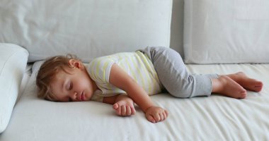 Cute baby sleeping slouched on sofa. Adorable infant boy toddler napping