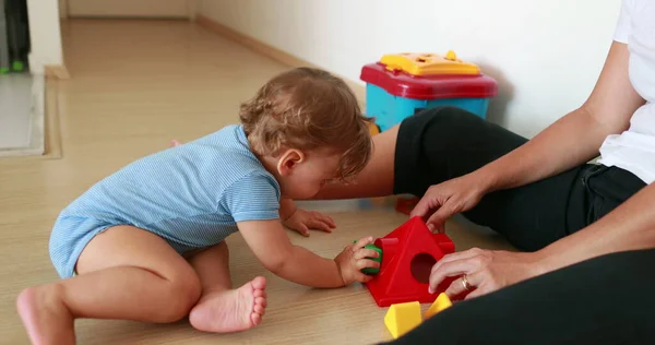 Cute baby playing indoors with toys. Mother and one year old infant relationship