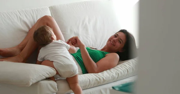 Mother Playing Baby Sofa Mom Lifting Infant Legs Candid Casual — 스톡 사진
