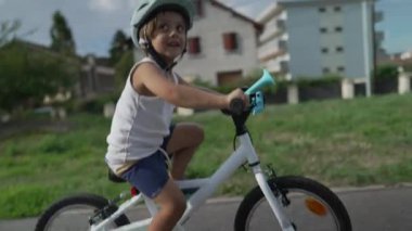 Dışarıda bisiklete binen heyecanlı bir çocuk. Kask takan çocuk bisikletçi bisiklet sürüyor.