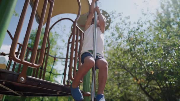 公園の外の遊び場の構造でポールに滑り降りる1人の小さな男の子 アウトドアを楽しんでいるアクティブな子供 — ストック動画