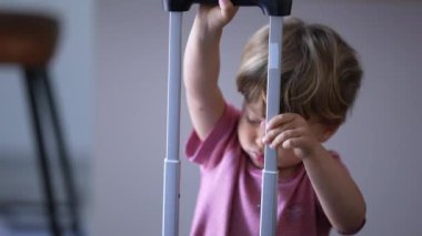 Child playing with luggage handle. One little boy preparing to travel with suitcase travel for trip