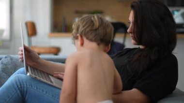 Anne bilgisayarı kullanarak evde bebek bebekle birden fazla iş yapıyor. Samimi yaşam tarzı ve gerçek hayatta anne çalışıyor ve ebeveynlik yapıyor.