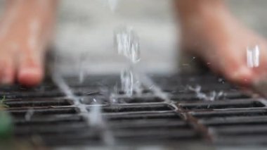 Water pouring into sewage system. Public water faucet droplets falling in slow motion