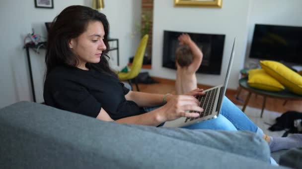 Woman Working Home Using Laptop Child Jumping Sofa Parent Front — Video Stock
