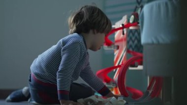 Yatak odasında tek başına oynayan samimi bir çocuk. Sıkılmış küçük çocuk yerde yatıp can sıkıntısı çekiyor.