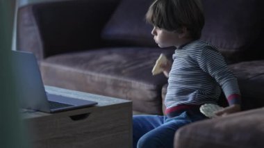 Gizli çocuk kanepeye oturmuş, ekranda çizgi film seyrediyor. Küçük bir çocuğun ev koltuğunda medya yiyip bitirdiği bir hayat tarzı.