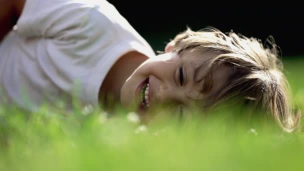 美しい晴れた日に芝生の上に置かれた楽しい子供の幸せな表情 ひとりの若い男の子が笑って笑っている 子供はくすぐられる — ストック動画