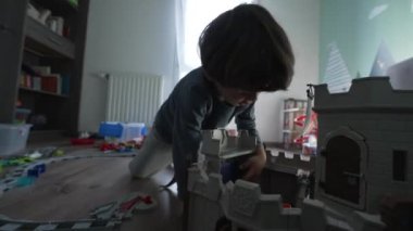 Küçük sevimli çocuk yatak odasında oyuncaklarla oynuyor. Çocuk evde kendi kendine oynuyor.