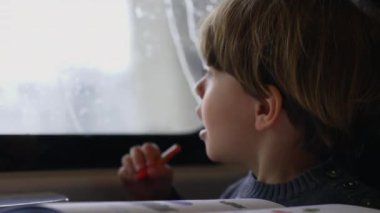 Trenin camından dışarı bakan heyecanlı bir çocuk manzarayı işaret ediyor. İçerideki mutlu yolcu çocuk pencere kenarında oturuyor.