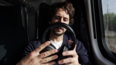 Trenle gidip gelirken kulaklık takan bir adam. Erkek yolcu, müzik podcast ya da sesli kitap dinleyerek ses geçirmez kulaklık takıyor
