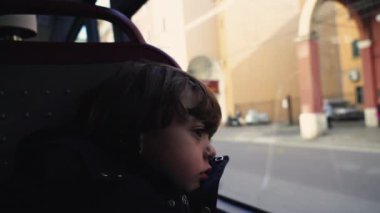 Otobüsün içinde derin derin düşünen küçük bir çocuk. Çocuk cam pencereye yaslanmış hüzünlü duygularla şehre bakıyor.