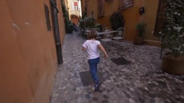 İtalyan mahallesinde koşan küçük bir çocuk. Tasasız çocuk ziyareti eski bir kaldırım taşında koşuyor.