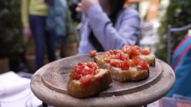 Kadın restoranda Tahta Tabak 'ta İtalyan aperatifi yiyor. Ekmek ve domates