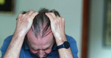 Older man covering face with hands, stressed and tired senior man in 70s feeling pressure
