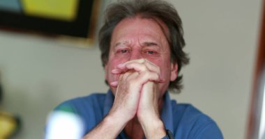 Older man feeling stressed covering face with hands. Anxious senior person in 70s