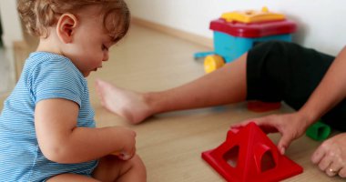 One year old infant baby boy throwing object away, child playing indoors during quarantine