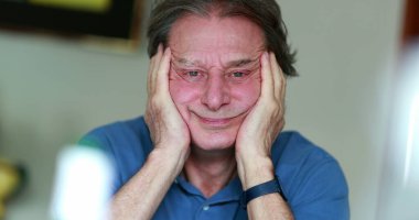 Senior man covering face with hands, older retired man rubbing face portrait