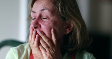 Stressed out older woman in 60s covering face with hands. Anxious worried senior woman feeling anxiety