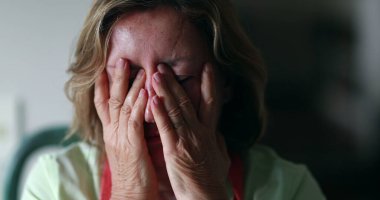 Stressed out older woman in 60s covering face with hands. Anxious worried senior woman feeling anxiety