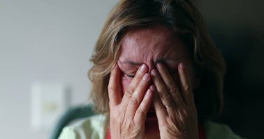 Worried older woman portrait feeling anxiety. Senior woman in 60s covering face