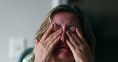 Worried older woman portrait feeling anxiety. Senior woman in 60s covering face