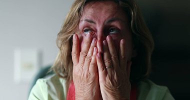 Worried older woman portrait feeling anxiety. Senior woman in 60s covering face