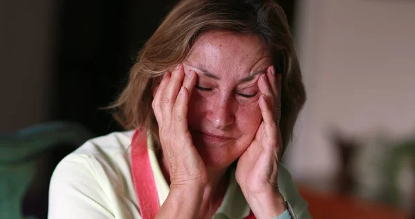 Older woman feeling stress and pain, anxious person covering face with hands feeling anxiety