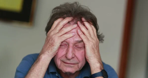 Stressed older man covering face with hands.Senior person feeling pain and stress