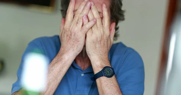 Tired anxious older man rubbing face with hands