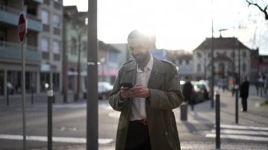 Şehirde yürüyen mutlu bir Faslı genç adam cep telefonuna gülümsüyor. Erkek bir Orta Doğulu gün batımında bir işaret fişeğiyle kaldırımda yürür.