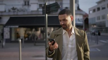 Sokağın ortasında telefonu kontrol eden Faslı genç bir adam. Ortadoğulu bir erkek akıllı telefonuyla mutlu görünüyor 