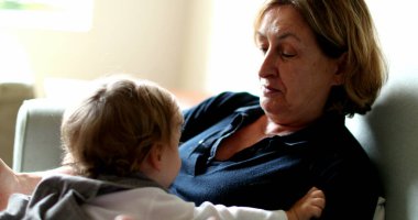 Baby leaving grandmother lap, multi generation family in couch