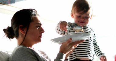 Mother feeding baby boy food. Mom and infant child eating meal