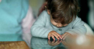 Playful Cute baby infant toddler playing with hands in table glass