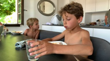 Çocuk öğle yemeği saatinde bir bardak su içiyor.